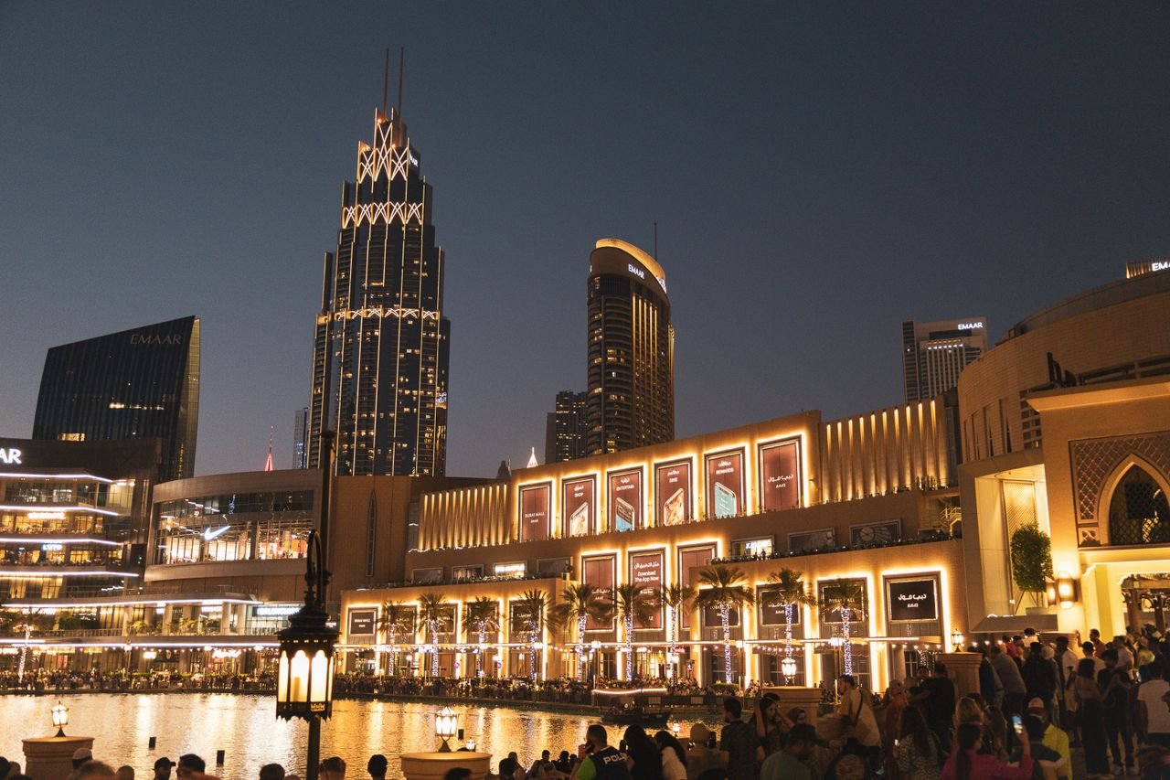 Illuminated skyscrapers and bustling cityscape of Downtown Dubai at night, capturing the vibrant urban life.